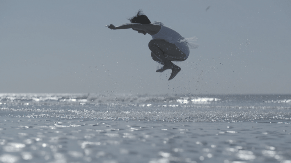 fotografia - kobieta w wyskoku nad taflą morza