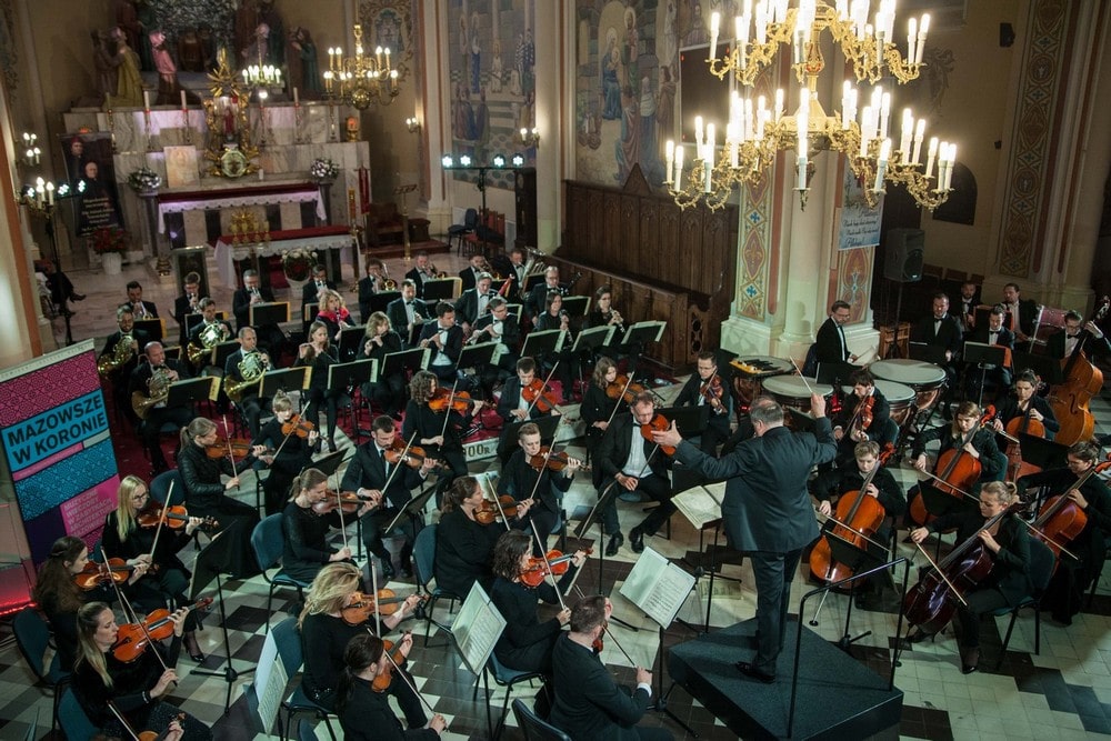 Fotografia: monumentalne wnętrze kościoła w Nasielsku, publiczność i orkiestra symfoniczna sfotografowana z góry