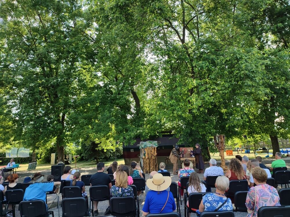 fotografia: publiczność oglądające spektakl plenerowy w parku Karawana Wędrujący Festiwal Sztuki i Animacji