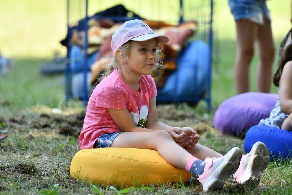 fotografia: dziewczynka siedzi na ziemi, ogląda spektakl