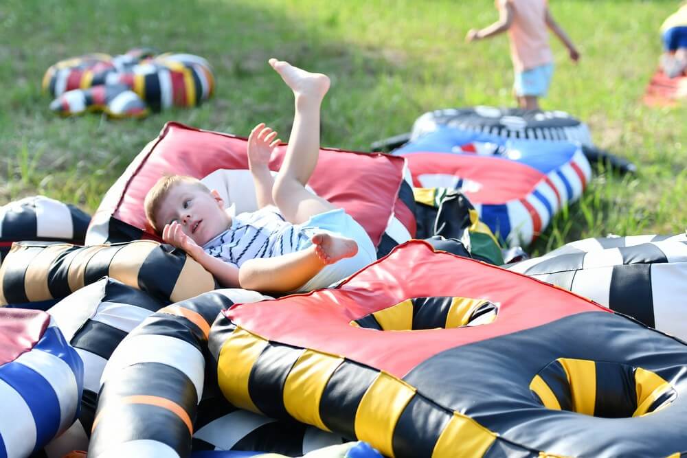 fotografia: chłopiec leży na stercie kolorowych poduszek