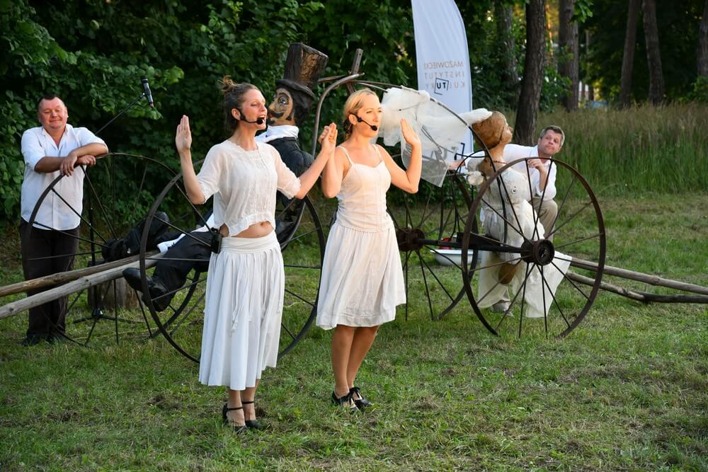 fotografia: scena ze spektaklu, dwie kobiety stoją obok siebie, w tle dwóch mężczyzn