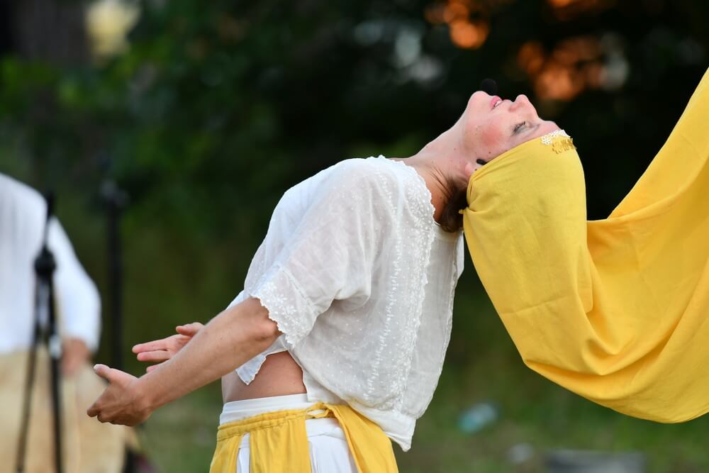 fotografia: kobieta w stroju scenicznym, odchylona do tyłu, na głowie ma żółtą hustę