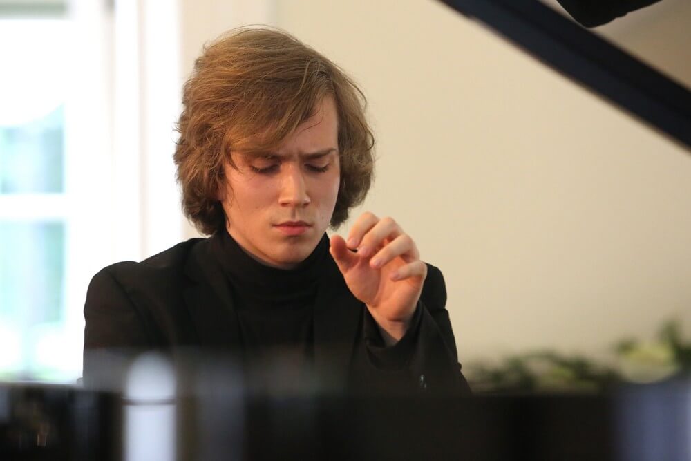fotografia: młody mężczyzna siedzi przy klawiaturze fortepianu