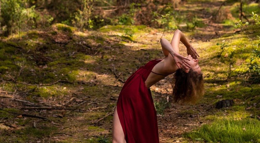 fotografia: Paulina Święcańska w czerwonej sukni na leśnej drodze, ekspresyjnie wygięta do tyłu