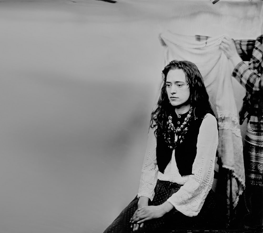 fotografia czarno biała siedzącej kobiety w stroju ludowym