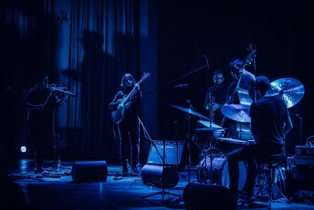 fotografia: niebieskie oświetlenie, pięcioro muzyków grających na instrumentach