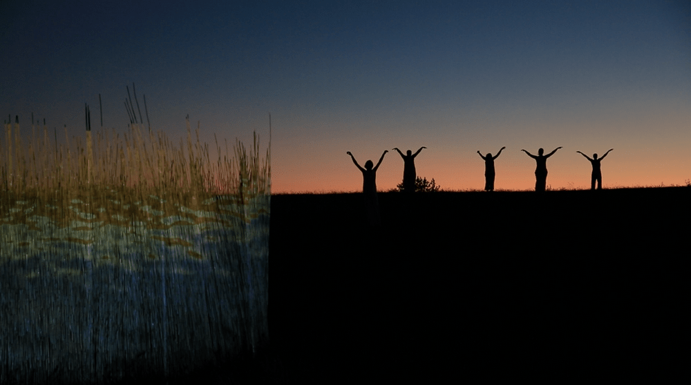 fotografia: na tle wieczornego nieba pięć sylwetek ludzkich, stoją z uniesionymi rękami