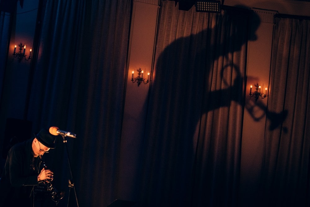 fotografia: Piotr Schmidt grający na trąbce, na ścianie wielki cień jego sylwetki