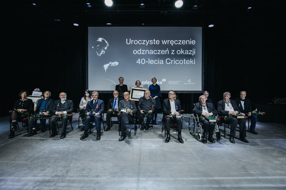 fotografia: kilkanaście osób siedzi na scenie, za nimi napis uroczyste wręczenie odznaczeń