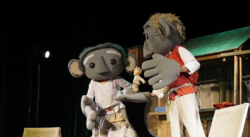 fotografia: dwoje aktorów na scenie, przebranych za lalki z dużymik głowami
