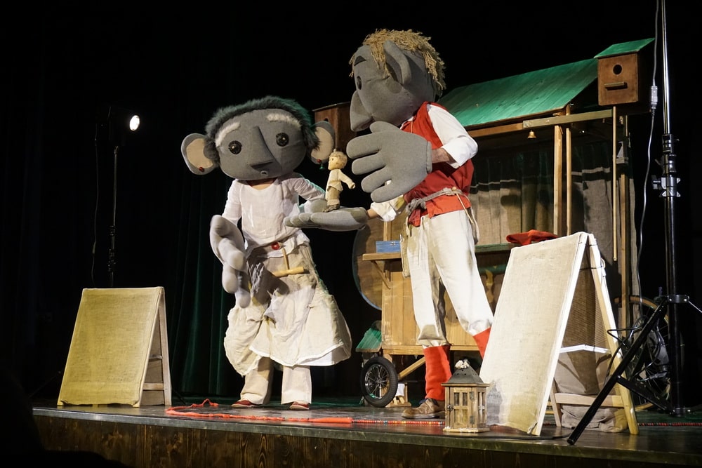 fotografia: dwoje aktorów na scenie, przebranych za lalki z dużymik głowami