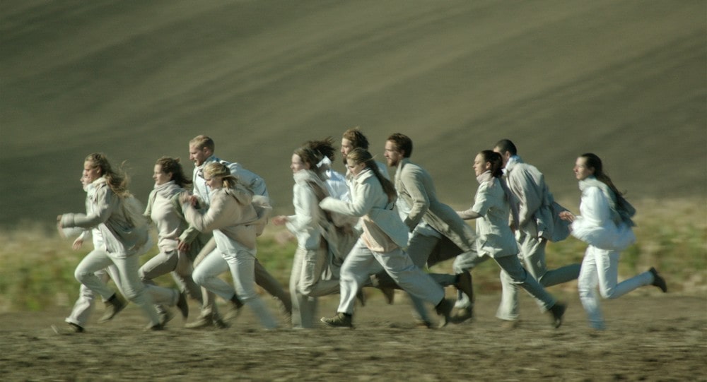 fotografia: grupa kilkunastu kobiet i mężczyzn w jasnych strojach biegnących razem w jednym kierunku