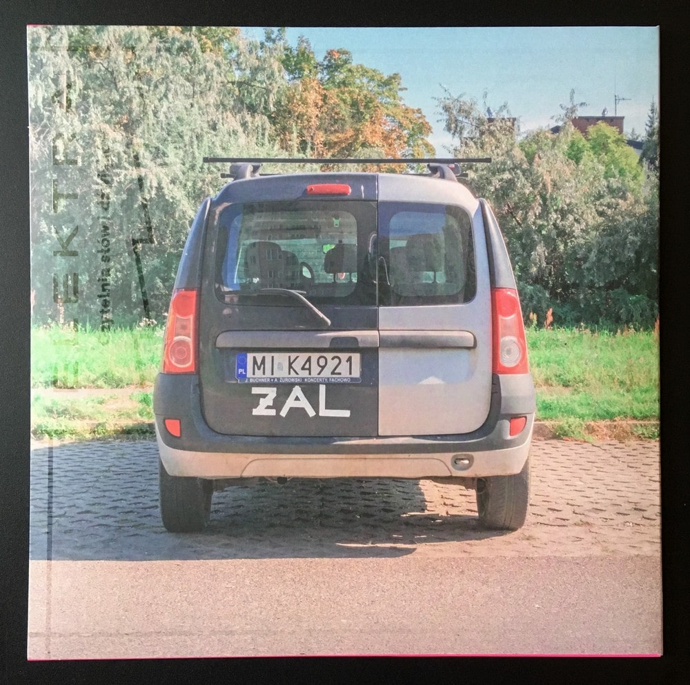 okładka płyty: fotografia tyłu samochodu z białym napisem żal