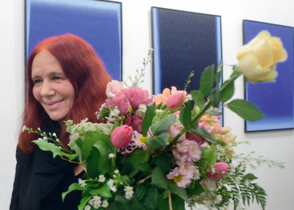 fotografia: dorota grynczel stoi z kwiatami, w tle obrazy