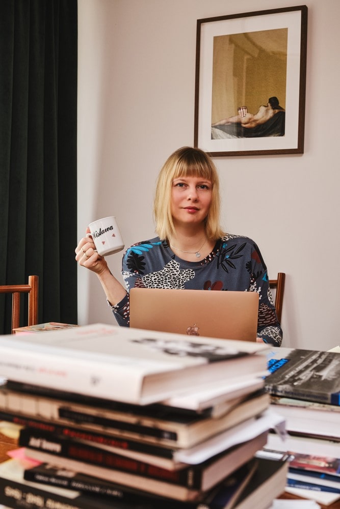 Fotografia: portret Karolina Sulej siedzi za biurkiem na którym leżą książki