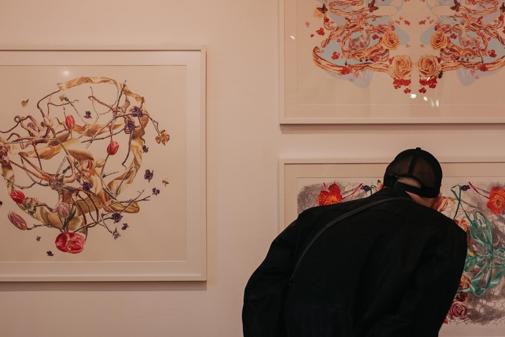 fotografia: osoba odwrócona tyłem, pochylona nad obrazem wiszącym na ścianie galerii