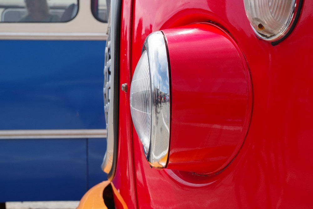 fotografia: karoseria czerwonego autobusu, zbliżenie na reflektor