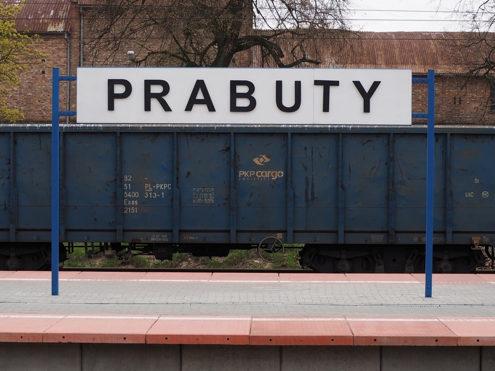 fotografia - stojąca na peronie kolejowym tablica z nazwą stacji kolejowej Prabuty