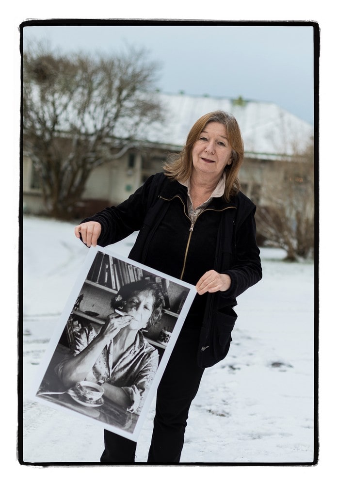 fotografia joanna helander stoi przed budynkiem trzymając w ręku dużą fotografię wisławy szymborskiej