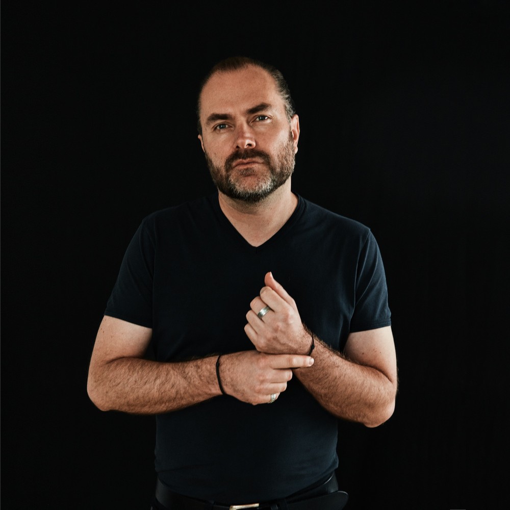 fotografia portret tomasza luterka, stoi w czarnej koszulce na czarnym tle