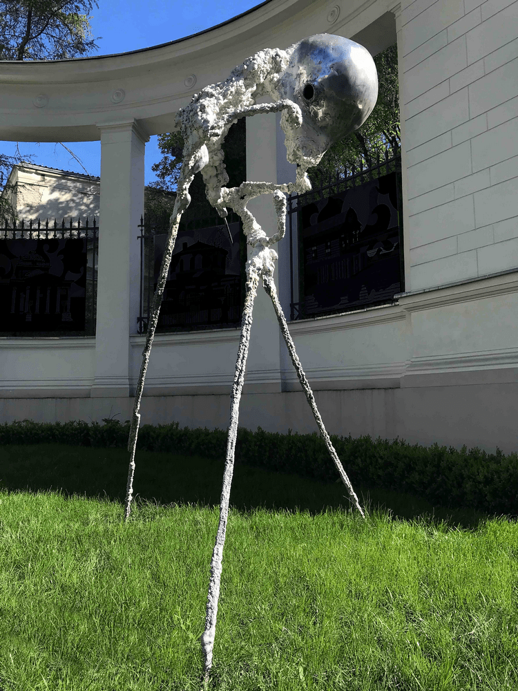rzeźba abstrakcyjna na trawniku przed budynkiem mik na tle kolumnady