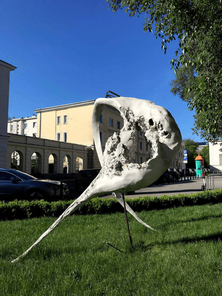 fotografia rzeźba abstrakcyjna na trawniku na tle budynków i błękitnego nieba