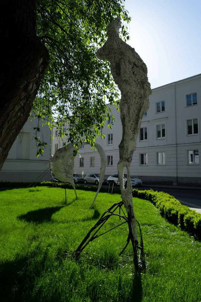 fotografia dwie rzeźby abstrakcyjne na trawniku na tle białego budynku i błękitnego nieba