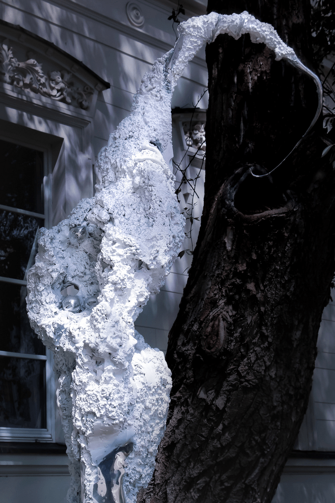 fotografia fragment rzeźby abstrakcyjnej na tle pnia drzewa