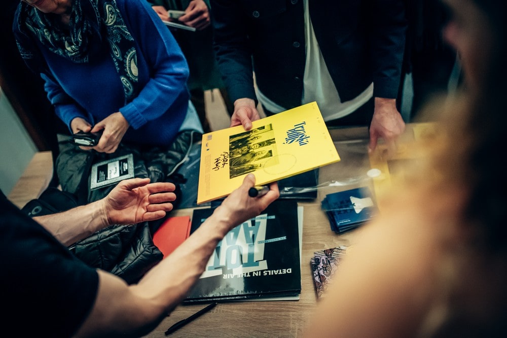 fotografia płyta z autografem podawana z ręki do ręki