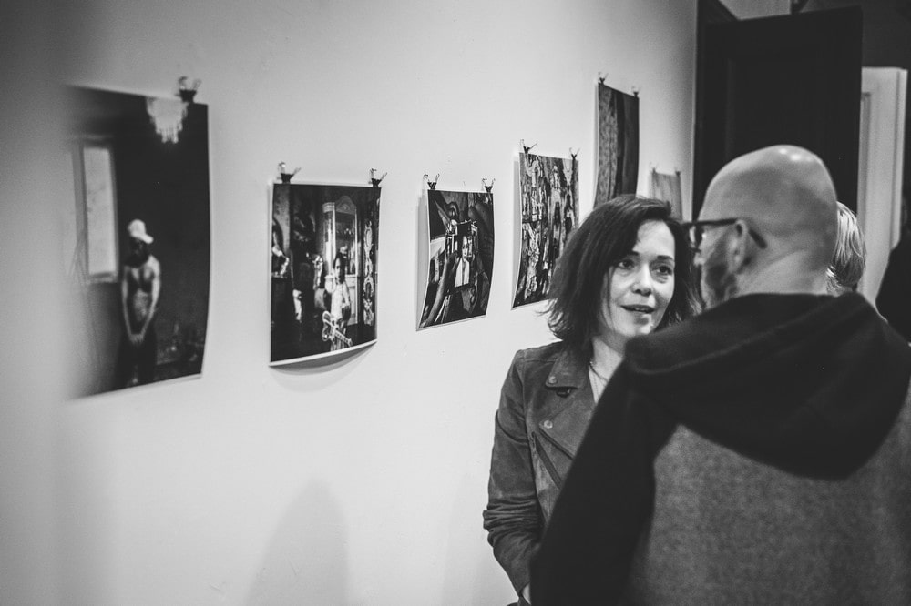 fotografia czarno biała kobieta i mężczyzna rozmawiają na tle fotografii wiszących na ścianie