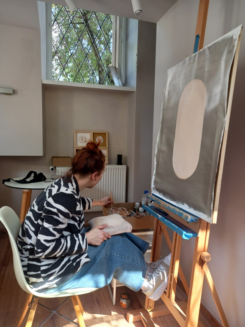 fotografia kobieta siedzi przed sztalugą w pracowni