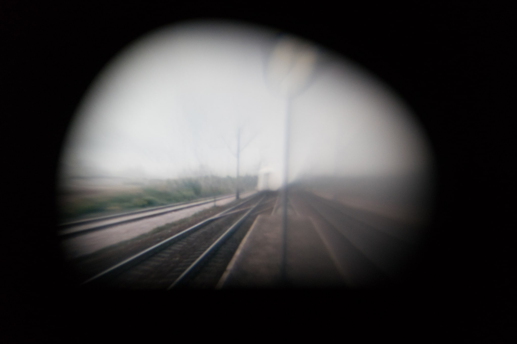 fotografia w czarnej otoczce widok na tory kolejowe i pociąg