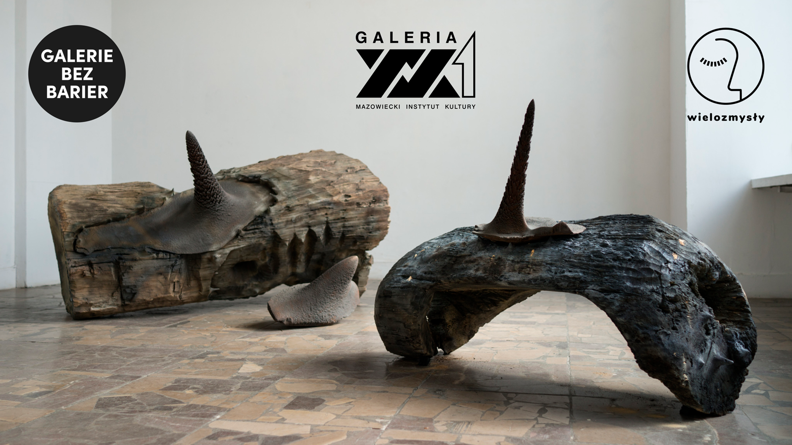 Grafika promocyjna: rzeźby Jana Musiałowskiego przedstawiające abstrakcyjne formy wyrzeźbione w drewnie, nad nimi logotypy Galerii bez barier, Galerii XX1 i Fundacji Wielozmysły.