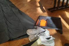 fotografia - para butów, rynienka z pomarańczową farbą i rozpostarta czarna folia, leżą na podłodze