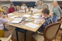 fotografia - grupa dzieci siedzi przy stole i rysuje