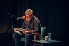 fotografia: Marek Lelek siedzi przed mikrofonem i czyta na głos